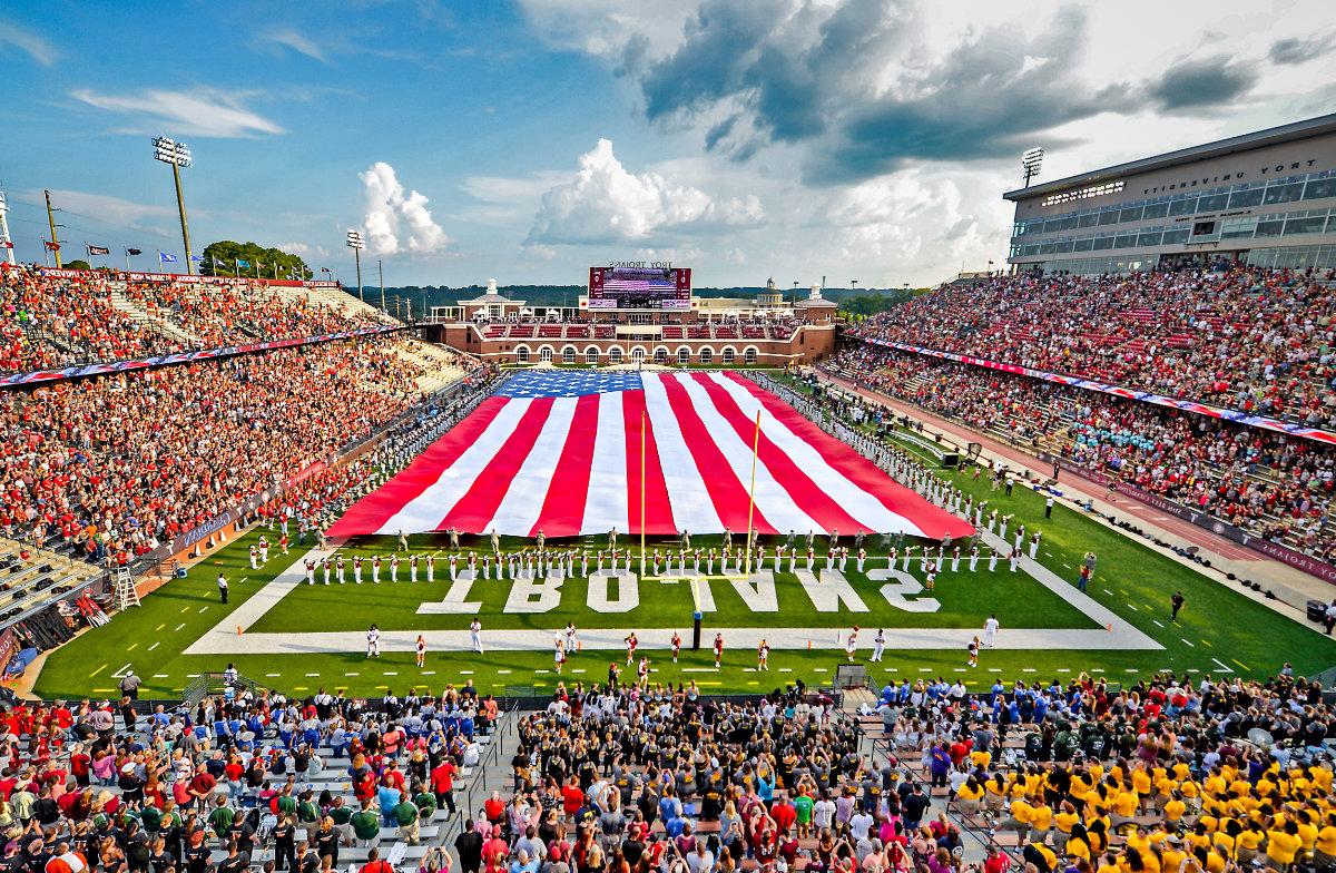 在军乐队的伴奏下，一面巨大的美国国旗在橄榄球场上飘扬